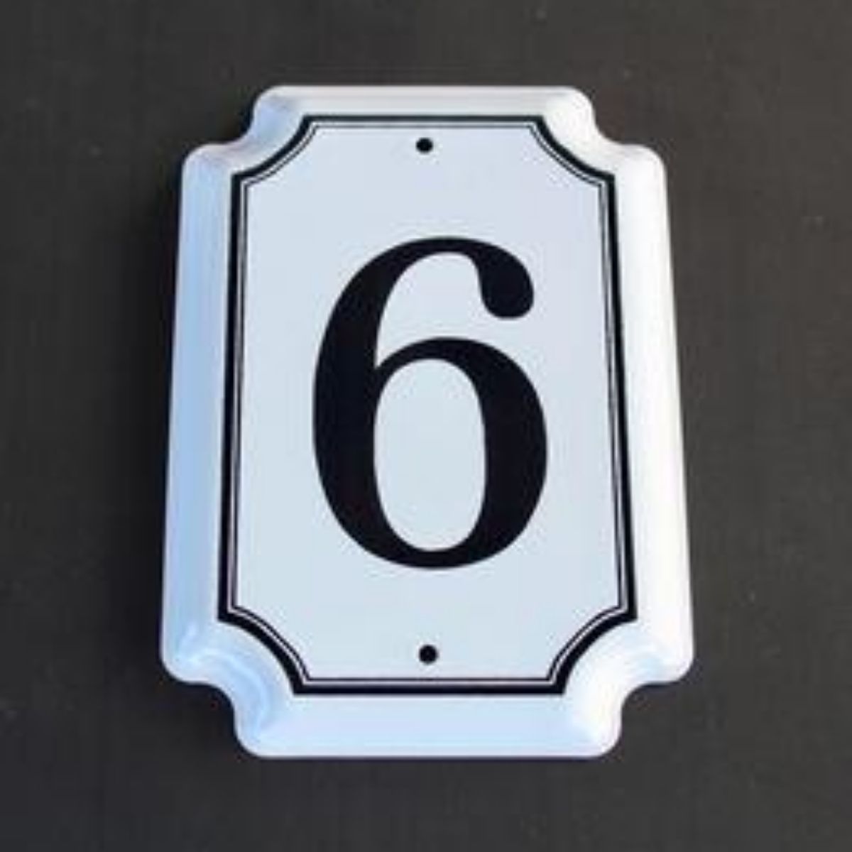 Traditional white enamel house number with the numeral in black, with a white border and screw holes visible.